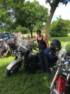 Person posing with motorcycle at outdoor event.