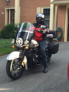 Motorcyclist in protective gear on driveway.