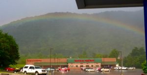 Rainbow over parking lot and store.