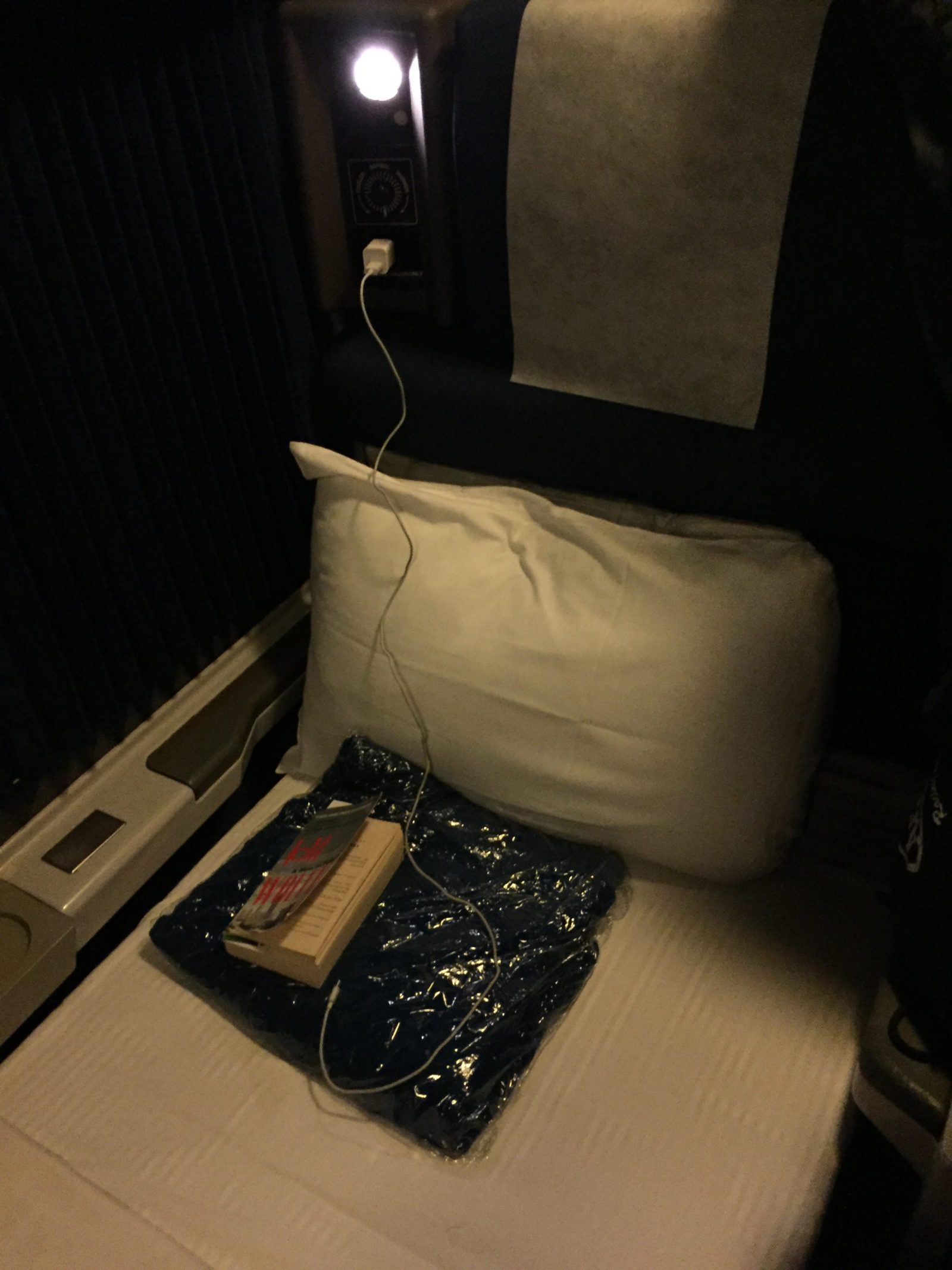 A pillow and a blanket on the floor of an airplane.