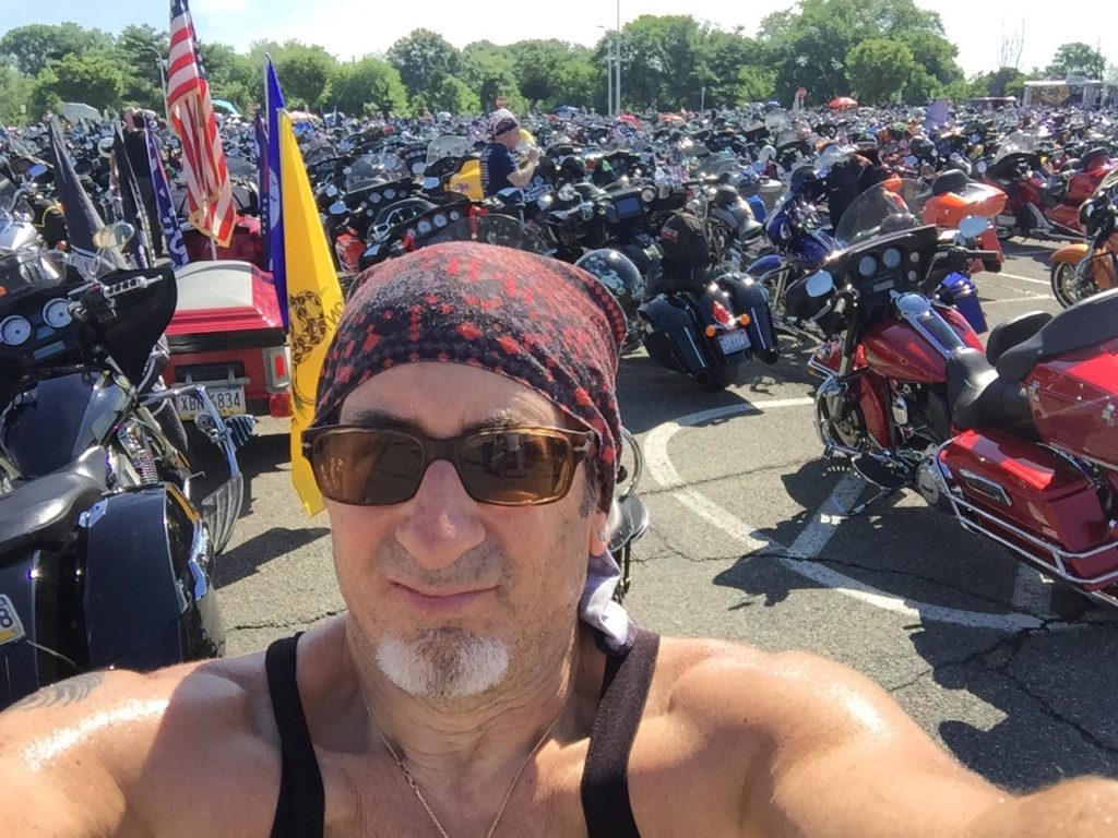 Man with motorcycles at outdoor gathering.