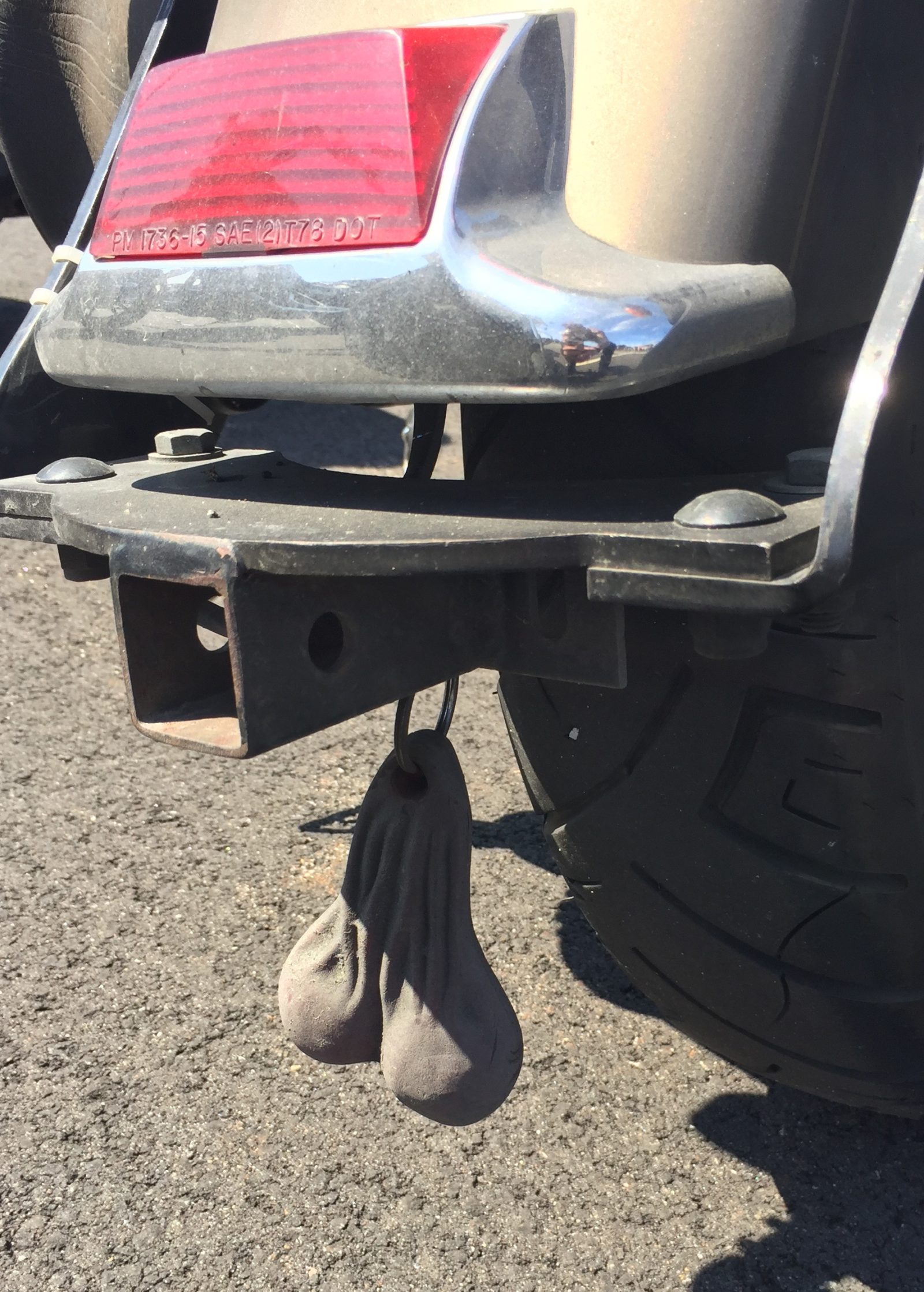 A pair of shoes hanging from the back of a motorcycle.