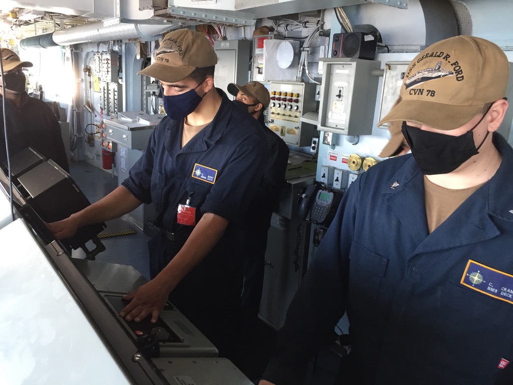 Crew members operating ship's control panels.