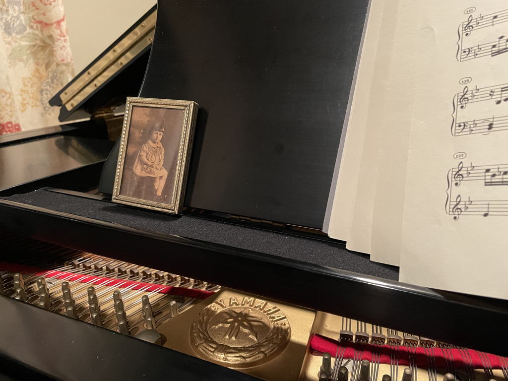 Piano with sheet music and framed photo.