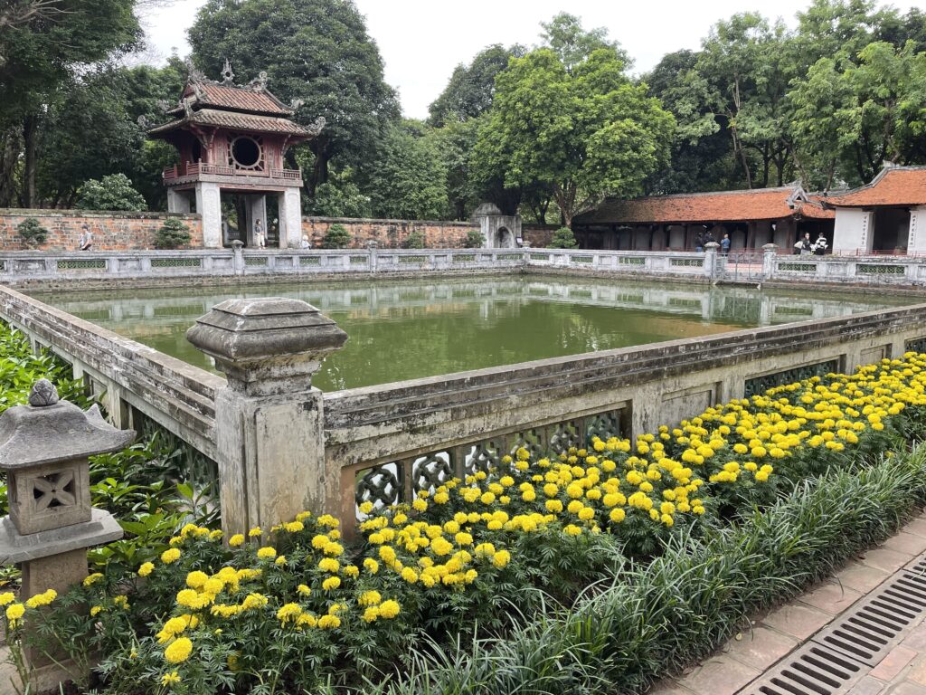 Temple courtyard with pond and yellow flowers.